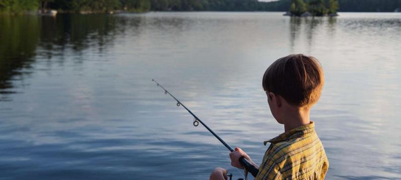 Boy fishing on edge of lake