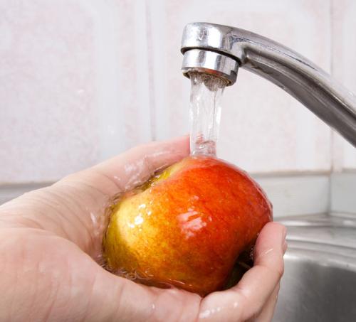 Washing an apple under a faucet