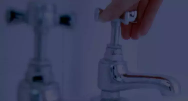 Hand turning a water faucet